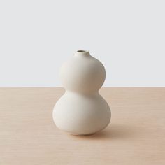 a white vase sitting on top of a wooden table