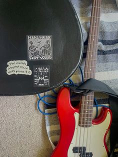 a red and white guitar sitting on top of a bed next to a black case