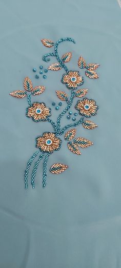 a blue table cloth with beaded flowers and leaves on it, along with beads