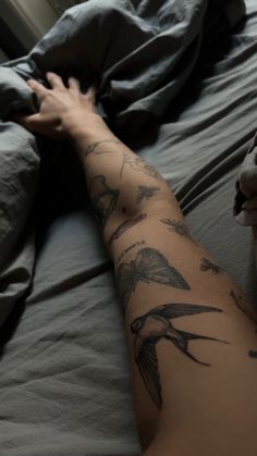 a person laying in bed with tattoos on their arm