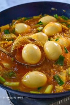 a blue bowl filled with stew and dumplings on top of a table next to a wooden spoon