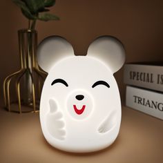 a white bear shaped night light sitting on top of a table next to two books