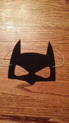 a wooden table with a batman mask cut out on the top and string attached to it