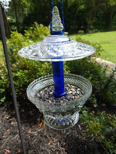 a blue glass bird feeder sitting on top of a tree