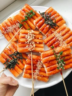 several skewered carrots are arranged on a white plate