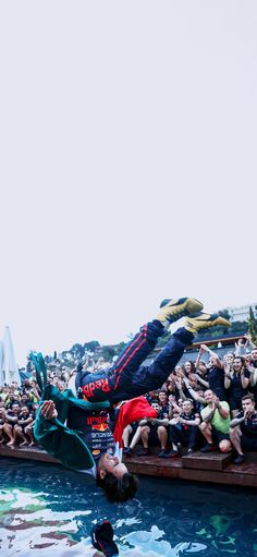 a man diving into the water in front of a large group of people