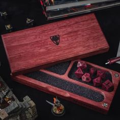 a wooden box filled with dice on top of a table next to other games and accessories