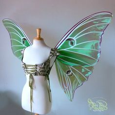 a white mannequin wearing a green butterfly costume