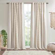 a living room with white curtains and a rug in front of the window that has fringes on it