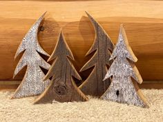 three wooden christmas trees are sitting on the carpet