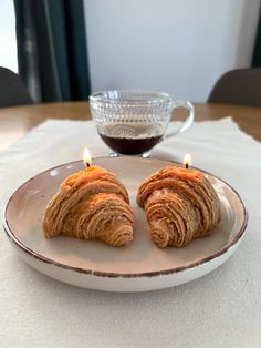 two croissants on a plate with a candle