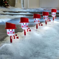 snowmen with red hats and scarfs are lined up in the snow