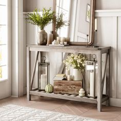 a console table with candles, flowers and a large mirror on the wall above it