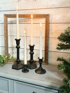 three candles sitting on top of a white mantle next to a mirror and christmas tree