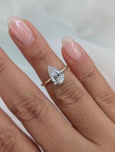 a woman's hand with a diamond ring on top of her finger and an engagement band