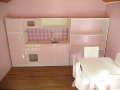 a doll house kitchen with pink walls and white furniture