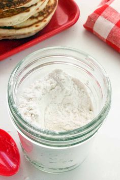 a glass jar filled with flour next to some pancakes