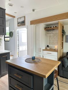 a kitchen island in the middle of a living room with grey cabinets and white walls