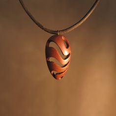 a wooden pendant hanging from a leather cord on a brown background with the word love written in it