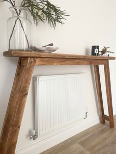 a wooden table with a glass vase on top and a radiator in the background