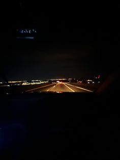 the view from inside an airplane at night, with lights in the dark and oncoming traffic