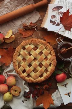 an apple pie on a table surrounded by autumn leaves, apples and other things to make it look like fall