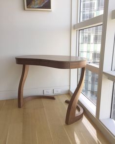 a wooden table sitting in front of a window next to a painting on the wall