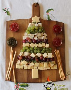 a christmas tree made out of cheese and grapes on a cutting board with crackers