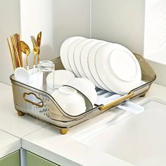 a tray filled with white plates and silverware on top of a counter next to a sink