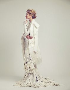 a woman in a white dress and fur coat posing for an article on fashion magazine