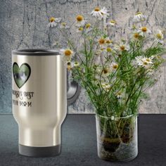 a vase filled with flowers next to a stainless steel tumbler