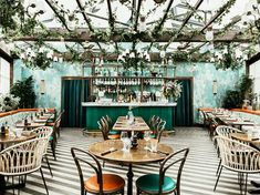 a restaurant with tables, chairs and plants on the wall above them is decorated in blue and green