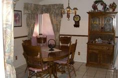 a dining room table with chairs and a clock on the wall