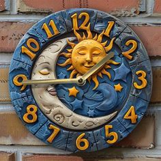 a blue and yellow clock on the side of a brick wall shows the sun and moon