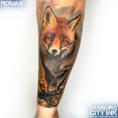 a fox tattoo on the leg of a person's arm, with leaves and flowers around it