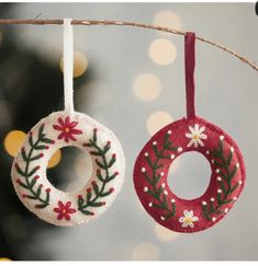 two ornaments hanging from a tree with lights in the background