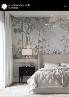 a white bed sitting under a window next to a wallpapered forest mural in a bedroom