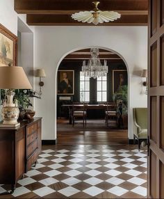 an entry way with a chandelier and checkered flooring in the hallway