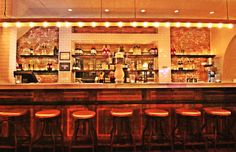 a bar with stools and lights behind it