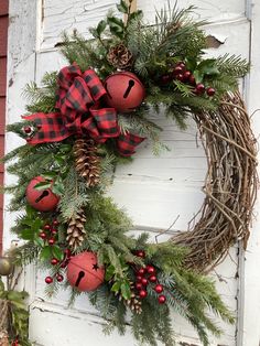 a christmas wreath hanging on the side of a door with pine cones and red balls