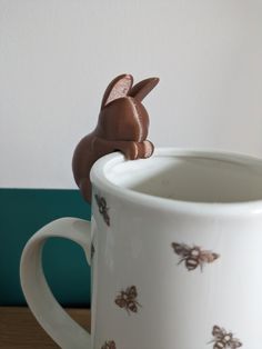 a white coffee mug with a chocolate bunny sitting on top of it's side