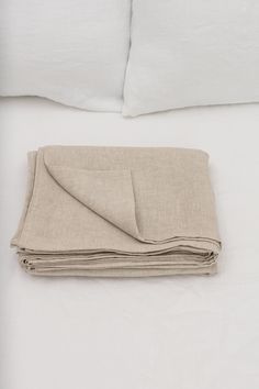 an unmade bed with two pillows and a blanket on top of it, next to a pillow case