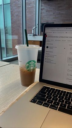 an open laptop computer sitting on top of a table next to a cup of coffee