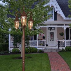 a lamp post in front of a house with lights on the top and side of it