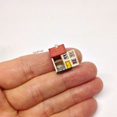 a tiny toy house sitting on top of someone's hand in front of a white background