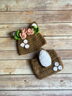 two crocheted hats with flowers on them sitting on top of a wooden table