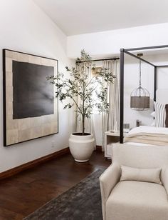 a bedroom with a large painting on the wall next to a white bed and chair