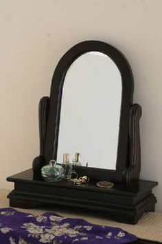 a mirror sitting on top of a wooden table next to a purple blanket and vase