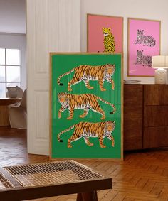 a room with two framed pictures on the wall and three tiger paintings on the floor