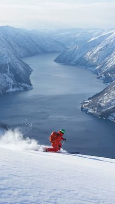 a person on skis going down a snowy hill near the water in the distance